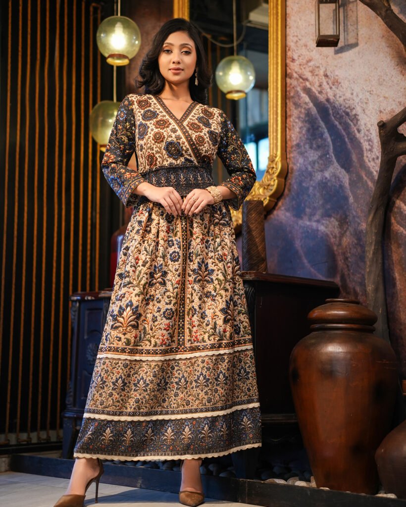 Model wearing ARIZA cream and navy smocked waist printed long tunic with a crossover V-neck and flared skirt.